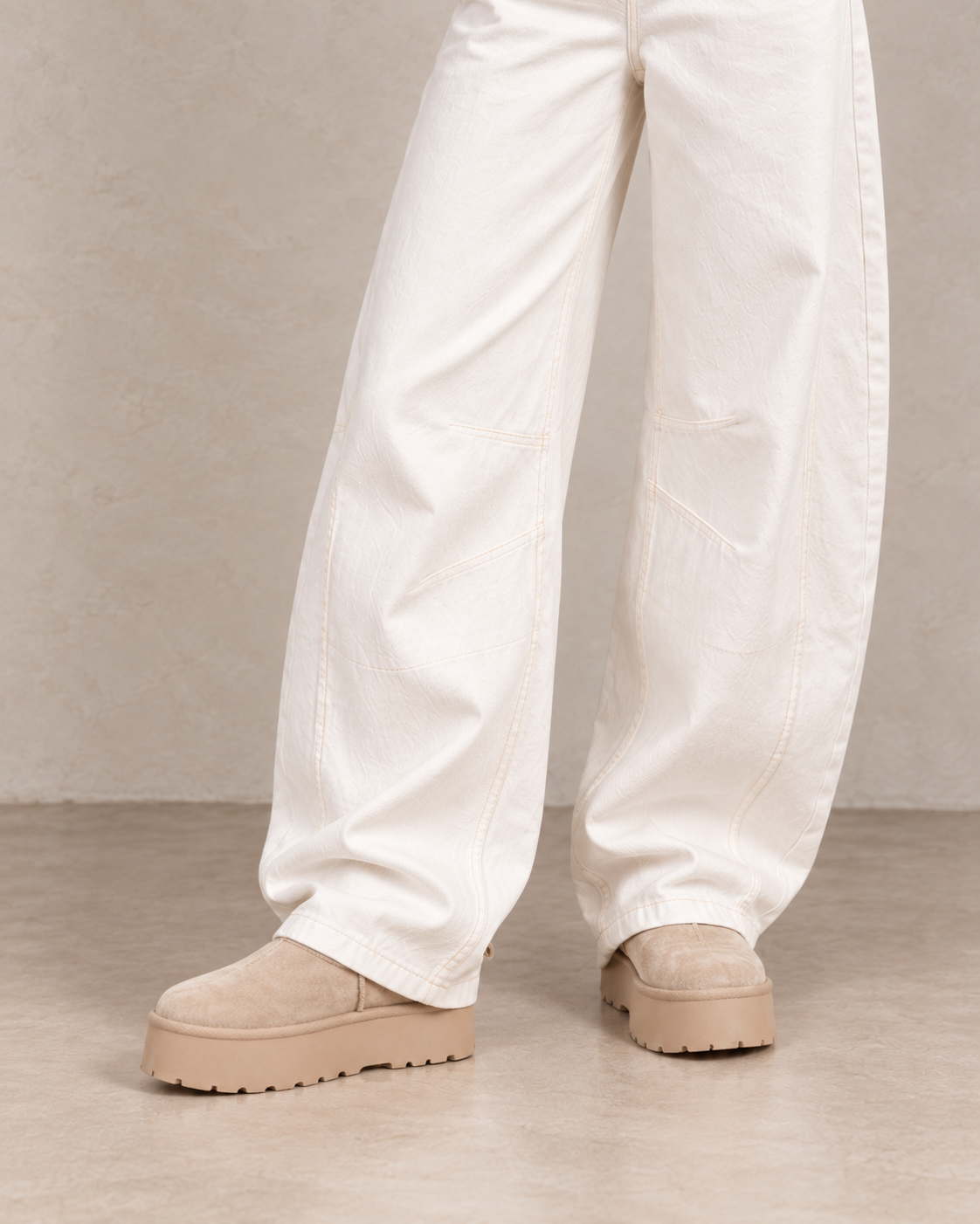 Close-up des bottines fourrées plateforme beige sous un jean barrel blanc