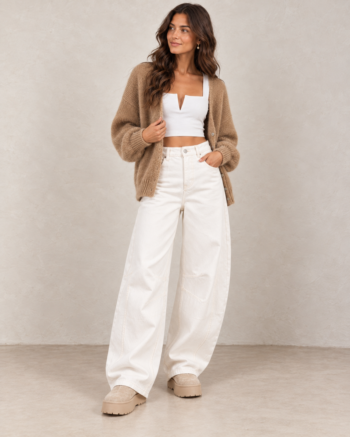 Bottines fourrées plateforme beige portées avec un jean barrel blanc, un top court blanc et un gilet camel