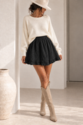 Jupe en gaze de coton noire portée avec un pull écru et des santiags