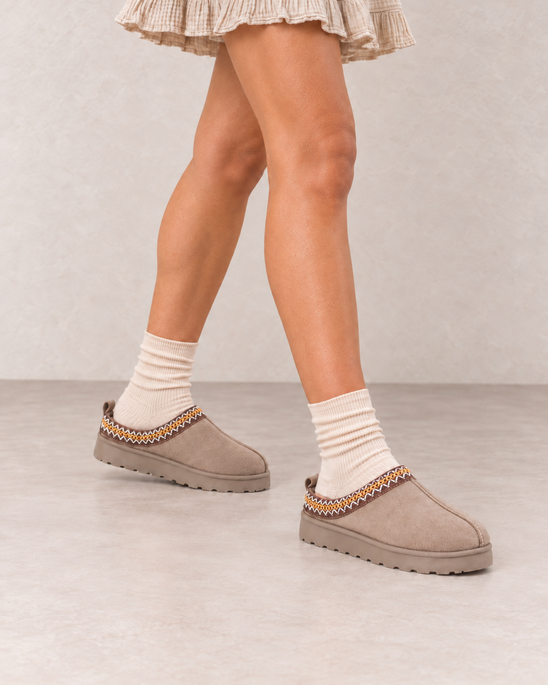 Close-up des mules fourrées taupe avec socquettes beige naturel couvrant le talon